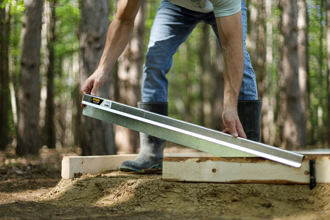 Contractor sliding a FormExtender onto a 2x4 concrete form