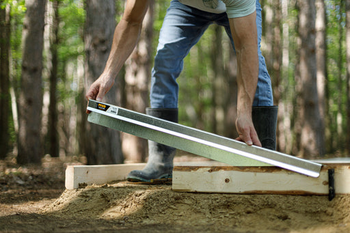 Contractor sliding a FormExtender onto a 2x4 concrete form