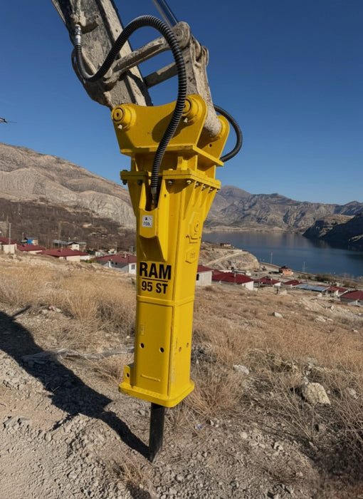 RAMEX RAM hydraulic breaker on an excavator at a waterside site, representative photo