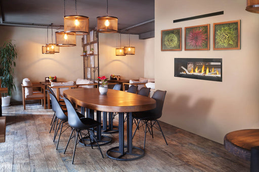 Napoleon Luxuria 50 see-through natural gas linear fireplace dividing a dining space with birch logs