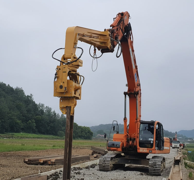 RAMEX auto-tilting vibro hammer driving a pile on an orange excavator