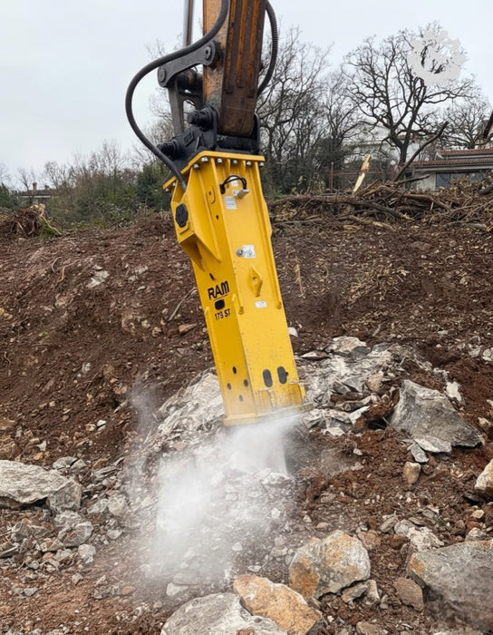 RAMEX RAM hydraulic breaker breaking concrete with dust rising, representative photo