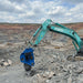 RAMEX RVR vibro ripper on a teal excavator at a rock site