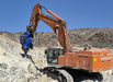 RAMEX RVR vibro ripper on an orange excavator in a rocky cut